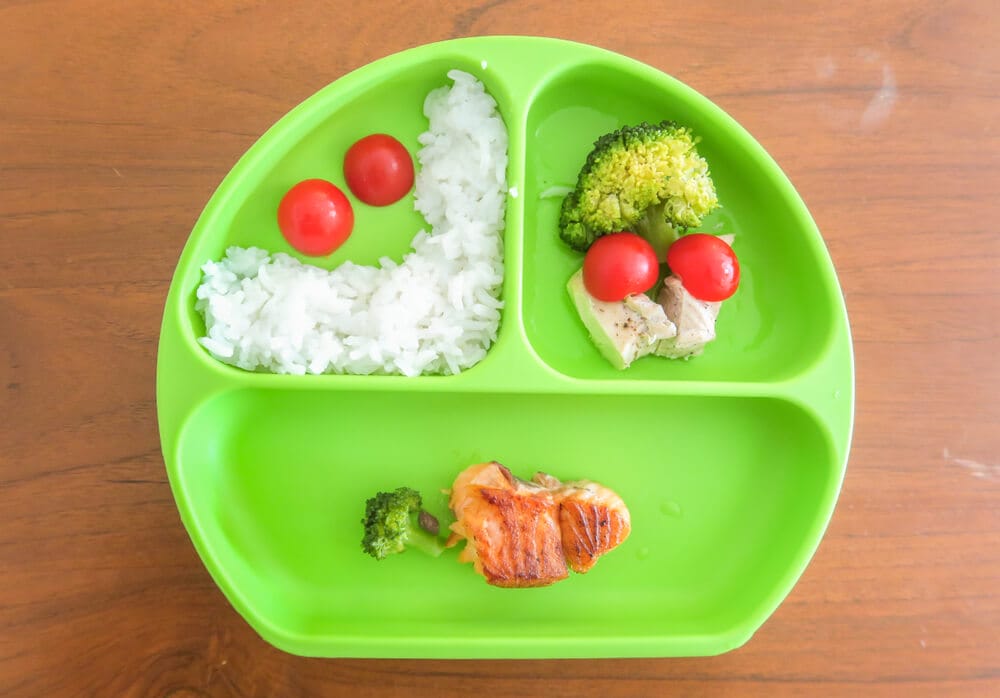 Plato de comida para bebé con arroz, brócoli, tomates cherry y salmón