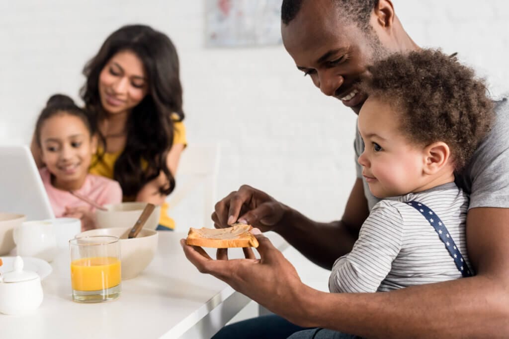 Familia con bebé de 1 año desayunando fruta y tostadas