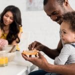 Familia con bebé de 1 año desayunando fruta y tostadas
